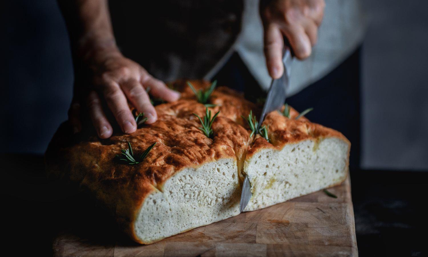 Chef cutting into a rosemary foccacia bread