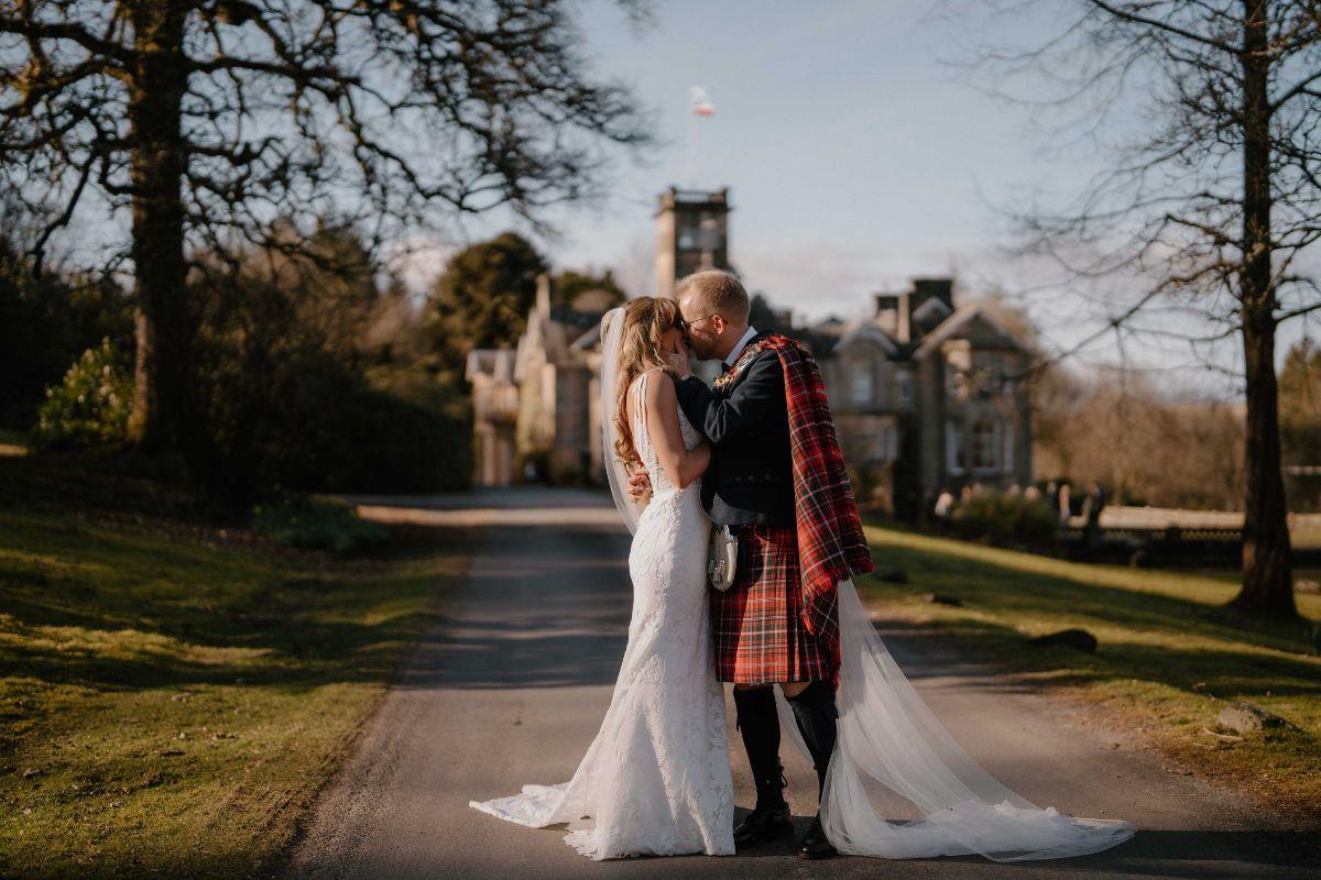 Newly married couple kissing in front of Auchen Castle