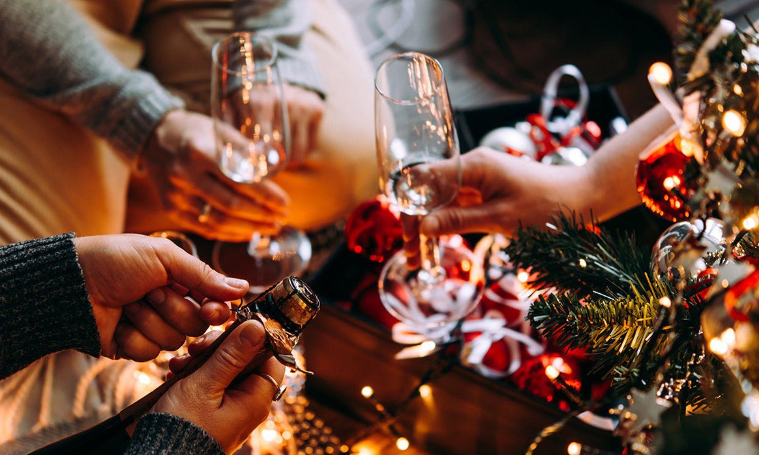 Hands holding champagne glasses near Christmas tree