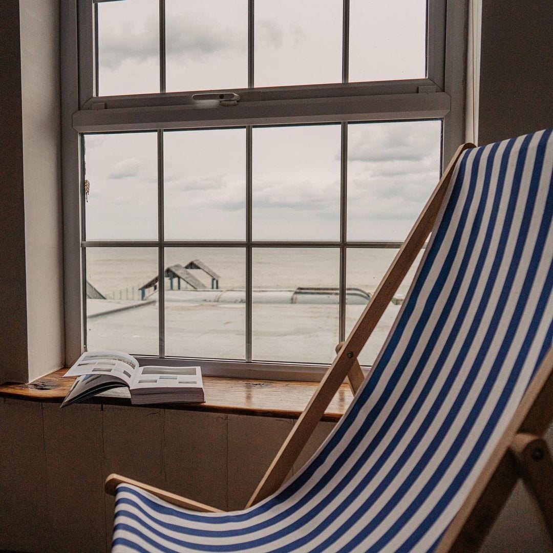 Striped deckchair by a window with view of the sea