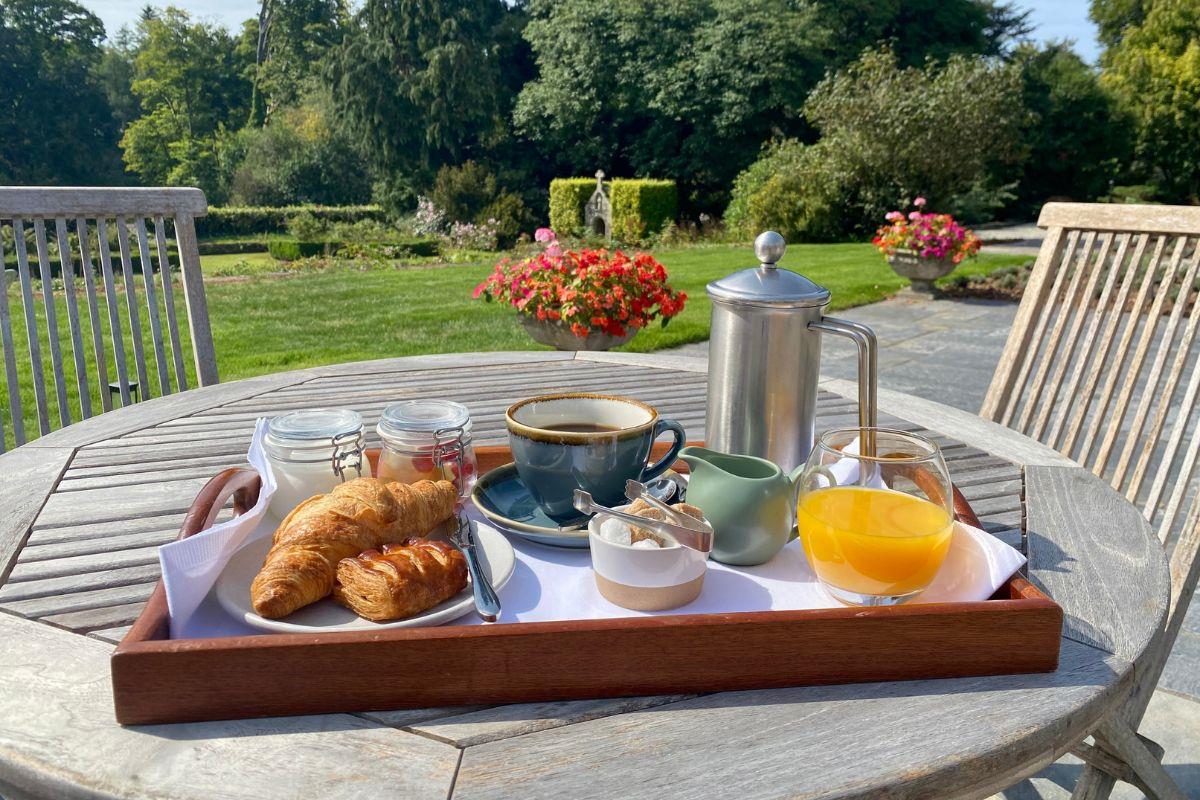 Continental breakfast served on a wooden table on a  sunny terrace