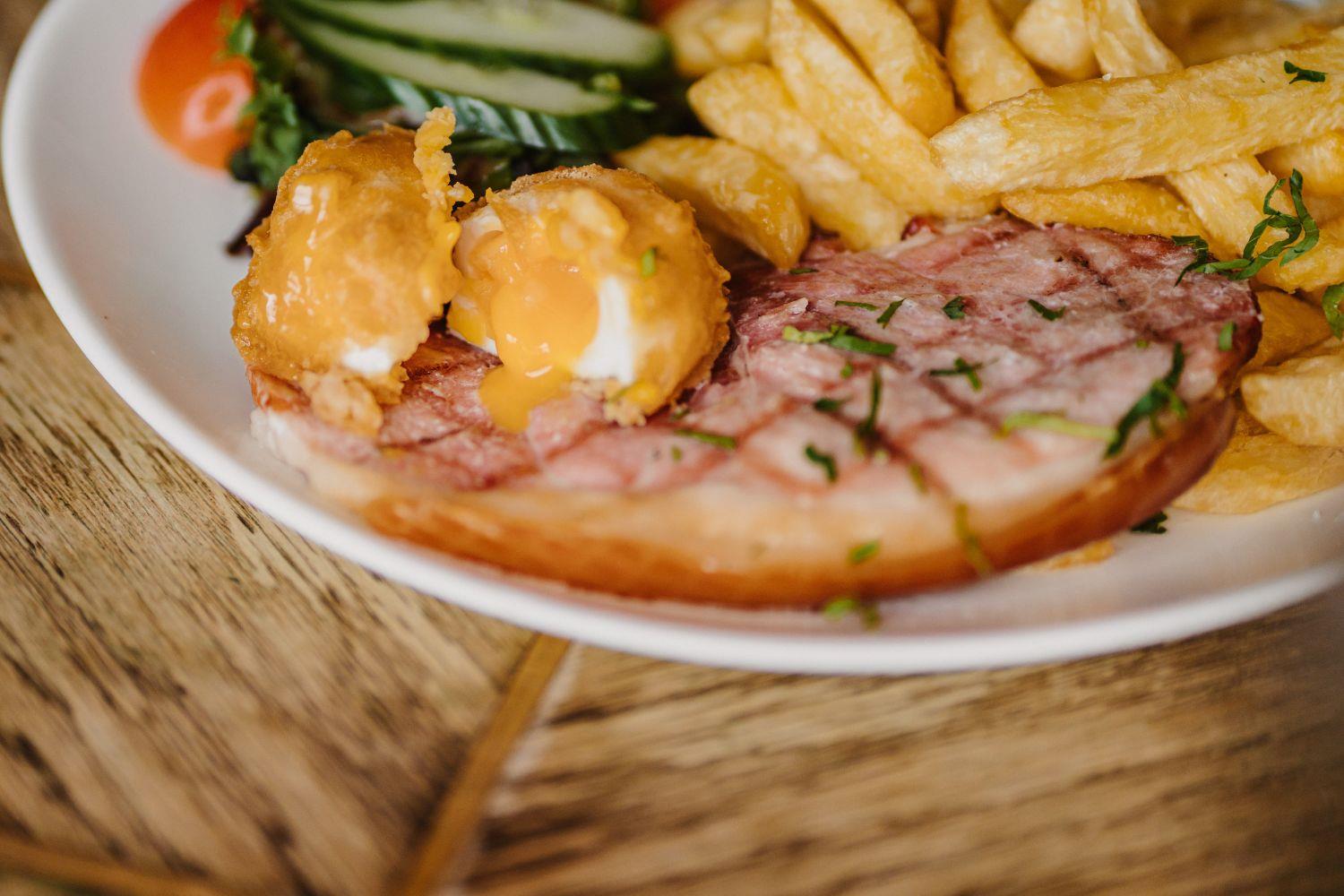 Gammon steak with battered poached eggs and salad on a plate
