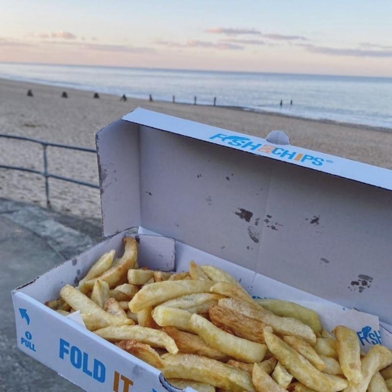 Fish and chips in a box overlooking sandy beach