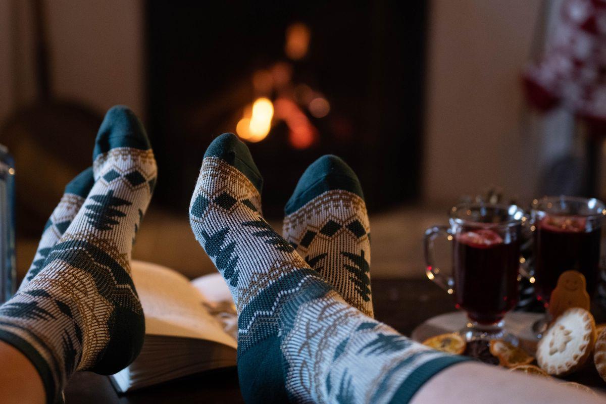Two pairs of feet in festive socks next to a fire with mulled wine