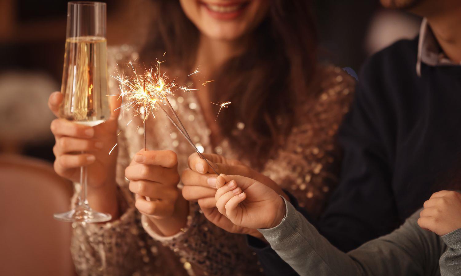 Woman holding a glass of champagne and a boy holding a sparkler