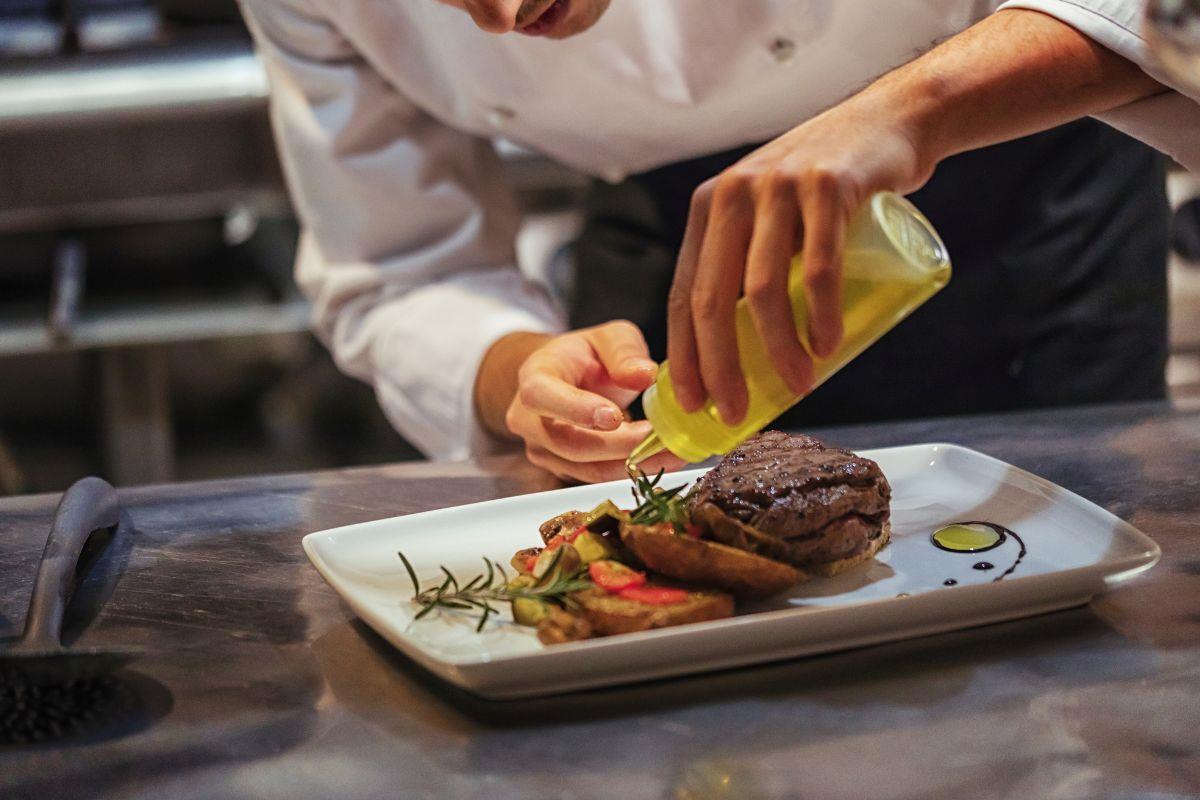 Kitchen assistant applying final touches to a dish in the kitchen
