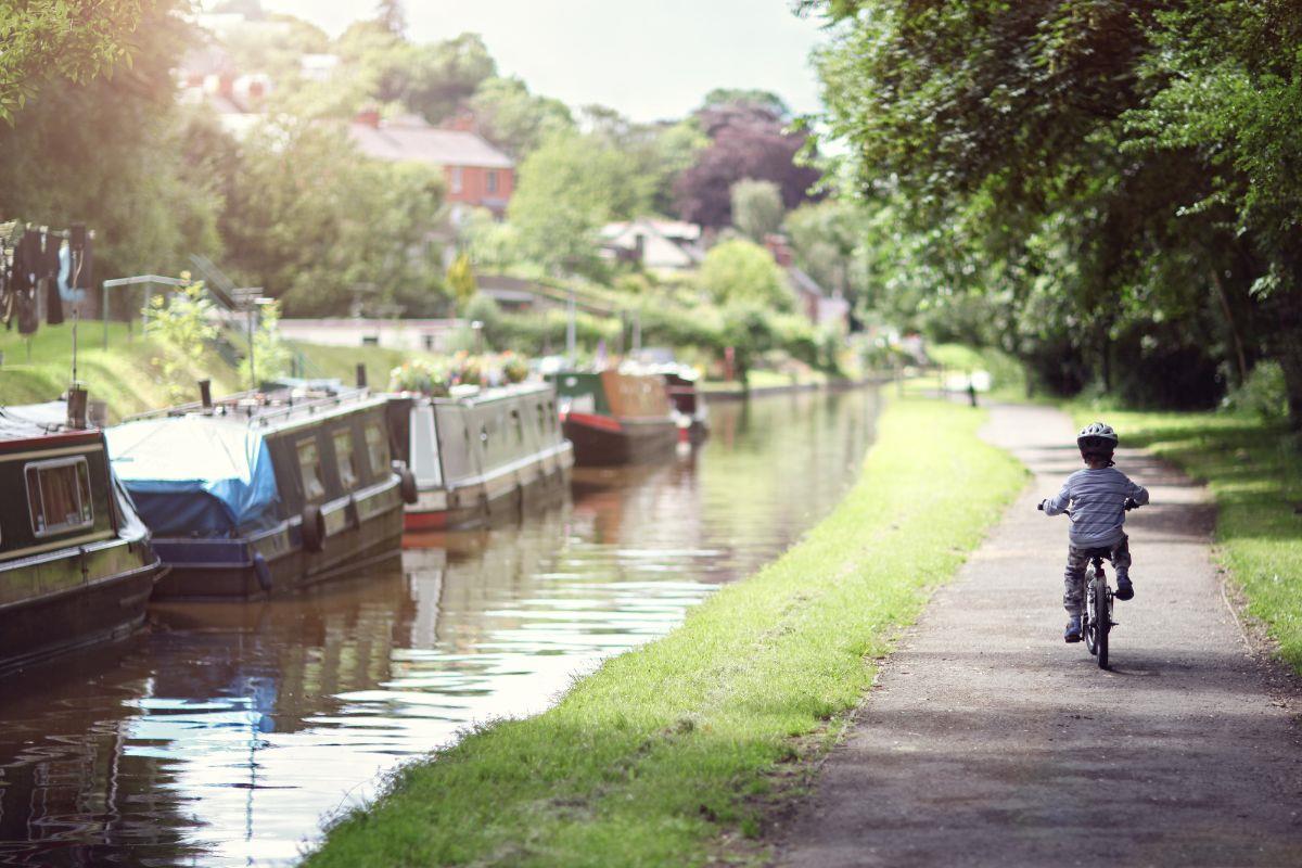 Child riding a bicycle along a canal towpath. Photo credit: Adobe Stock