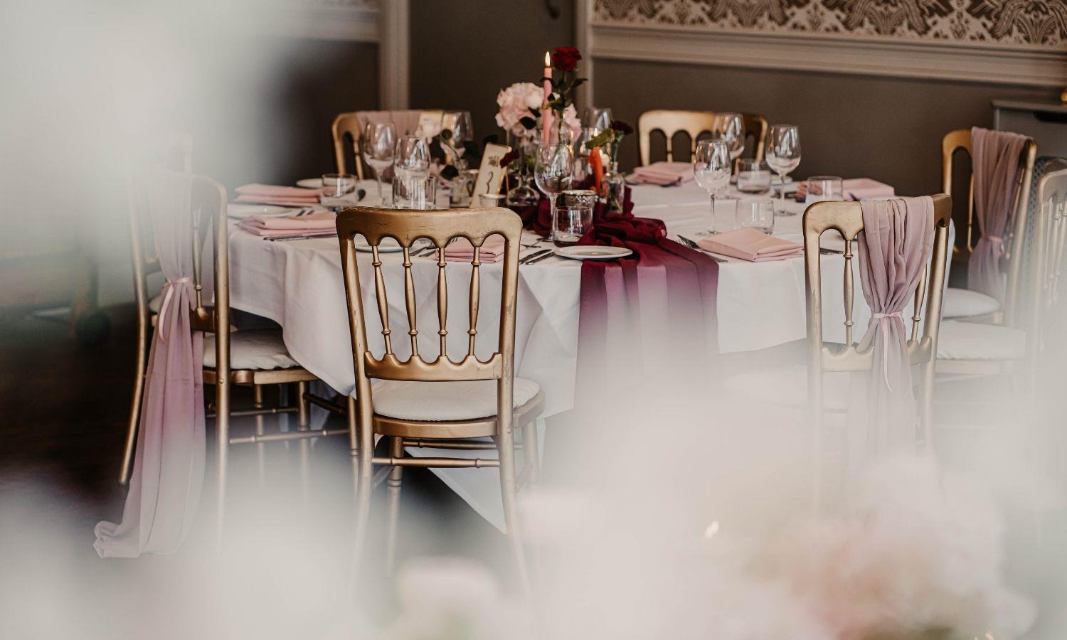 Round wedding table set up in pink and purple scheme with cold chairs