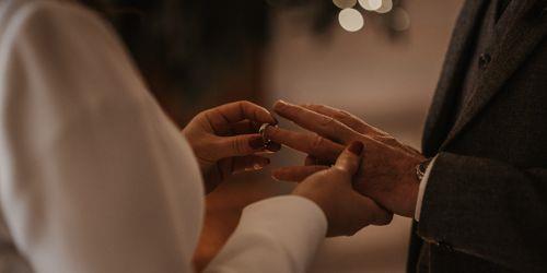 Woman placing a wedding band on a man's wedding finger