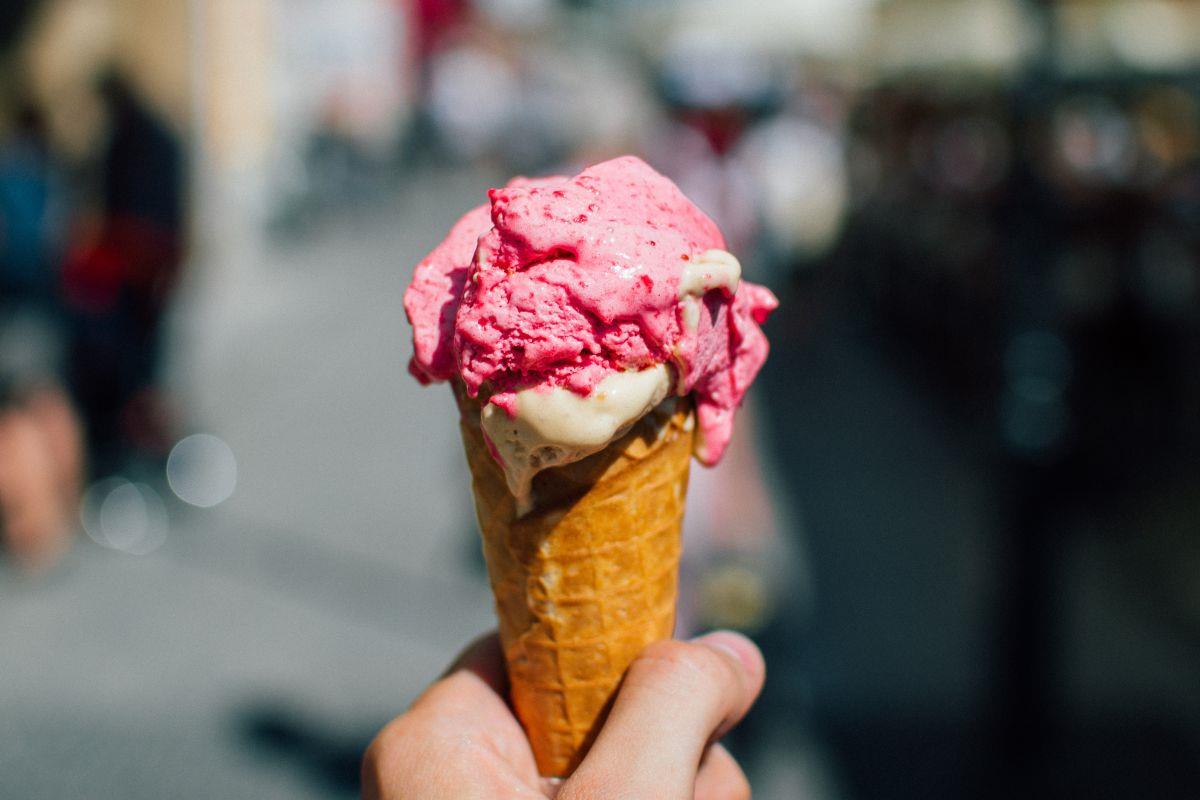 Person holding a pink ice-cream in a waffle cone