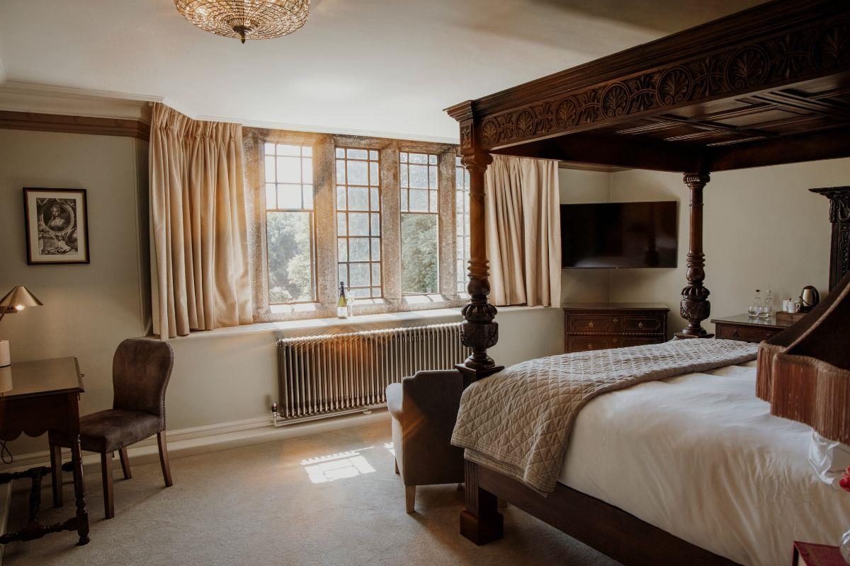 Luxurious looking bedroom with a four-poster bed filled with natural light from Manor House windows