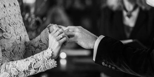 Woman putting a wedding band on a man't finger