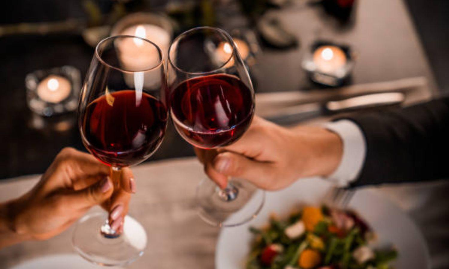 Couple at dinner doing a 'cheers' with two glass of red wine