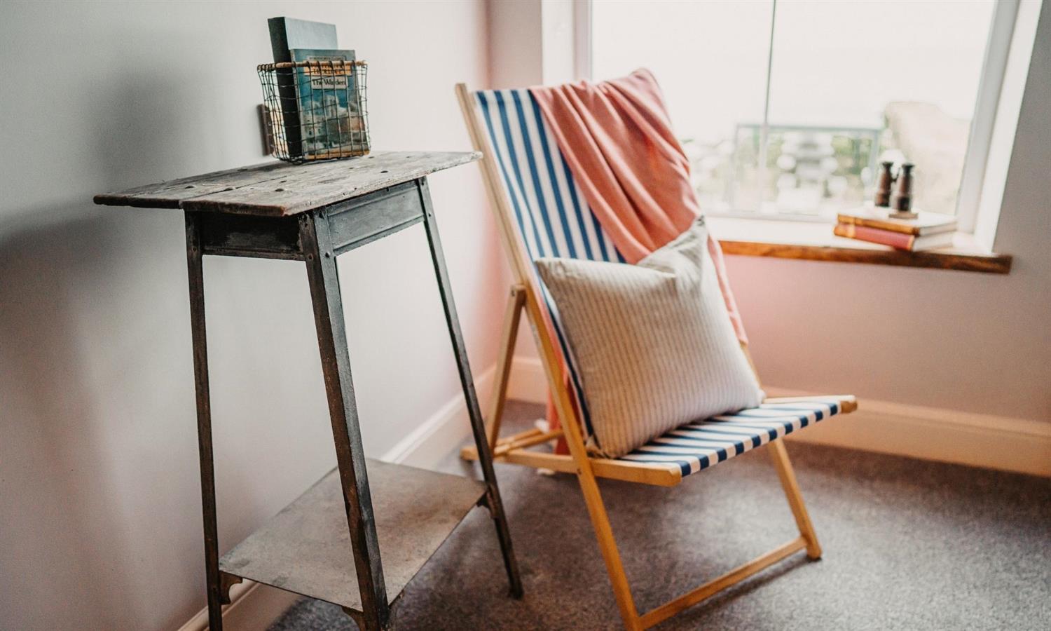 Striped deckchair by a window with view of the sea