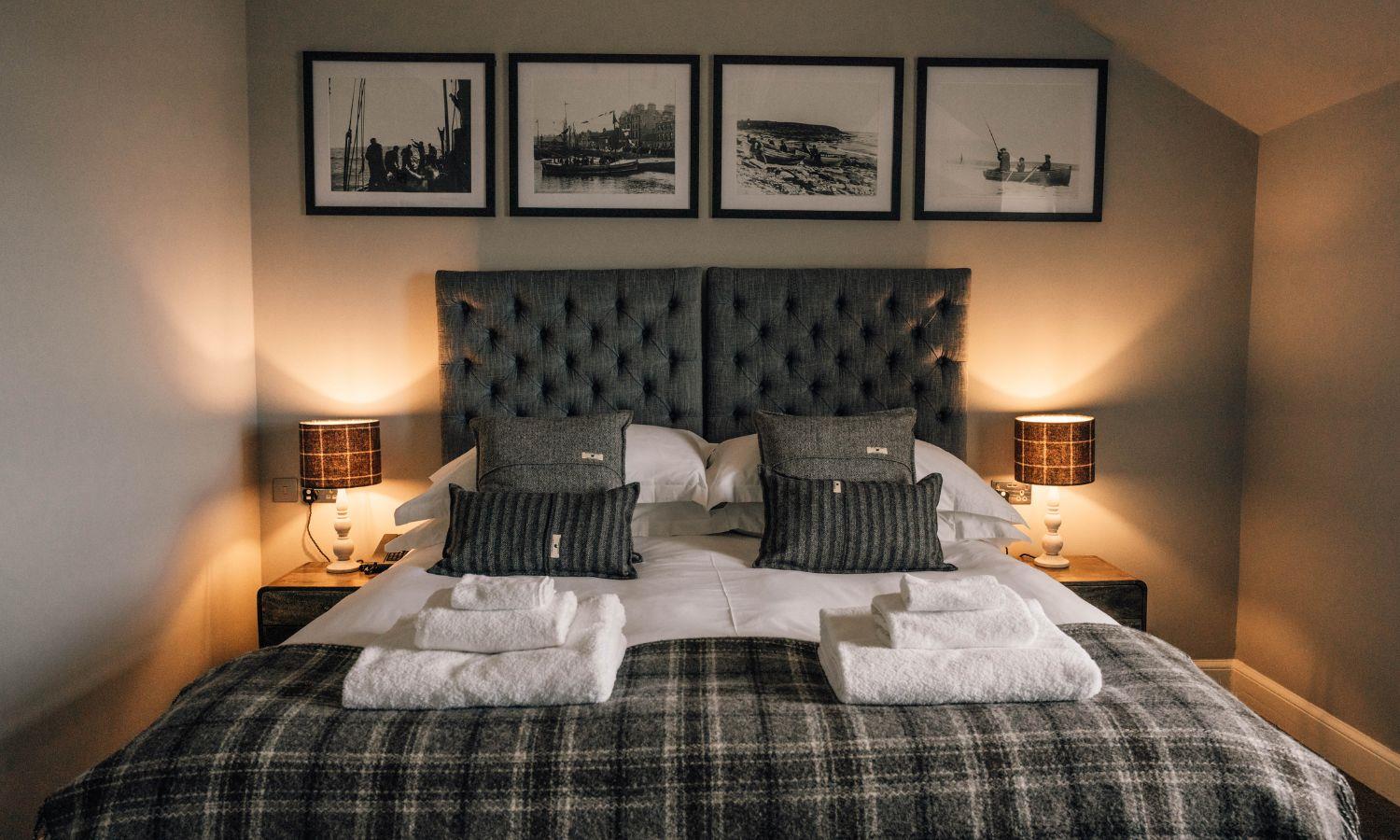Cosy hotel bed with tartan bedspread and folded towels