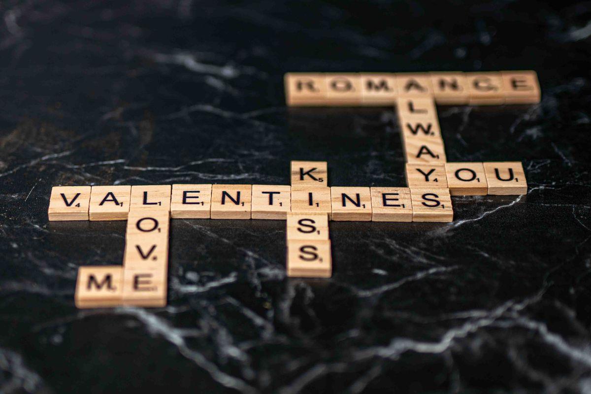 Wooden scrabble letters spell out words related to love on a black and white marble background