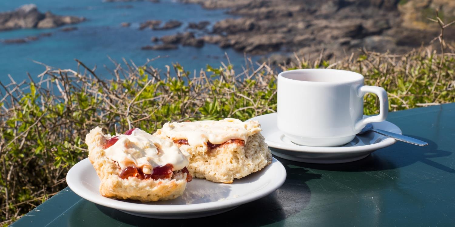Cream tea with a cup of tea overlooking the sea