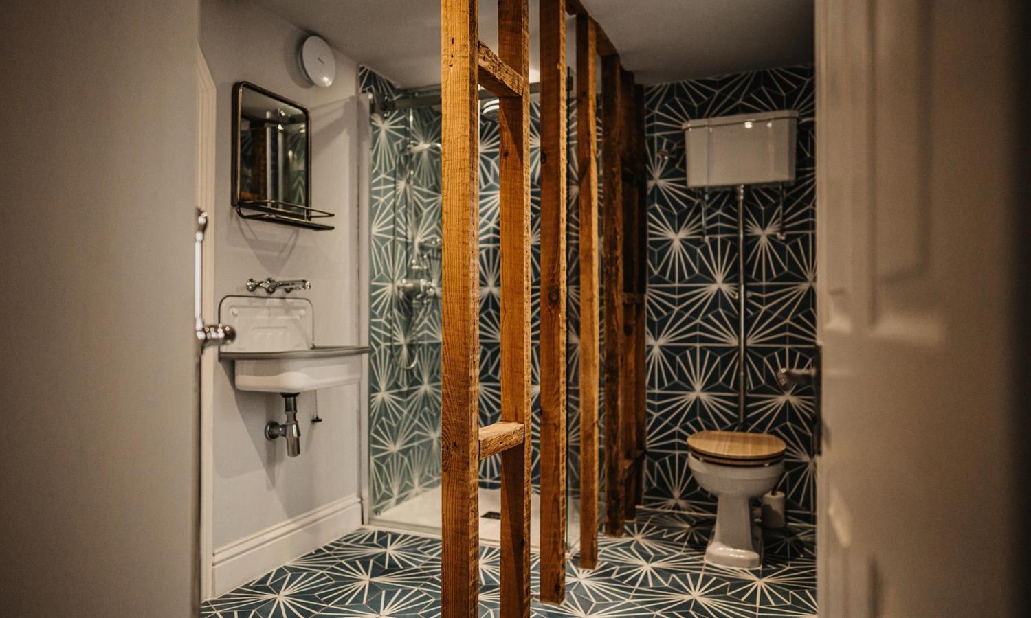 Deluxe Sea View bathroom at The Ship Inn with statement tiles, wooden features and couples' shower