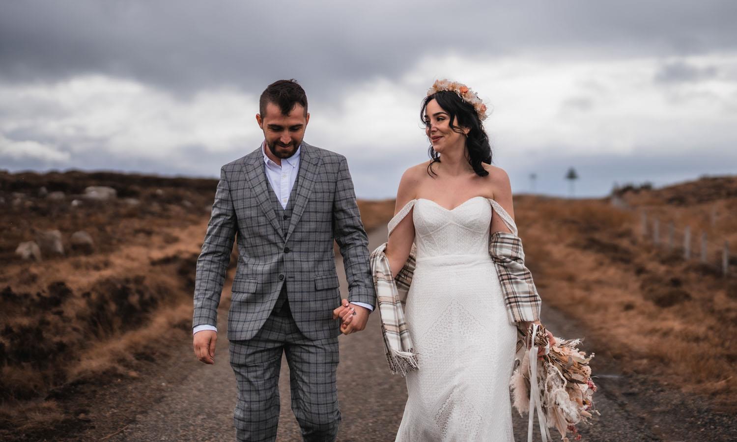 wedded couple walking along highland road