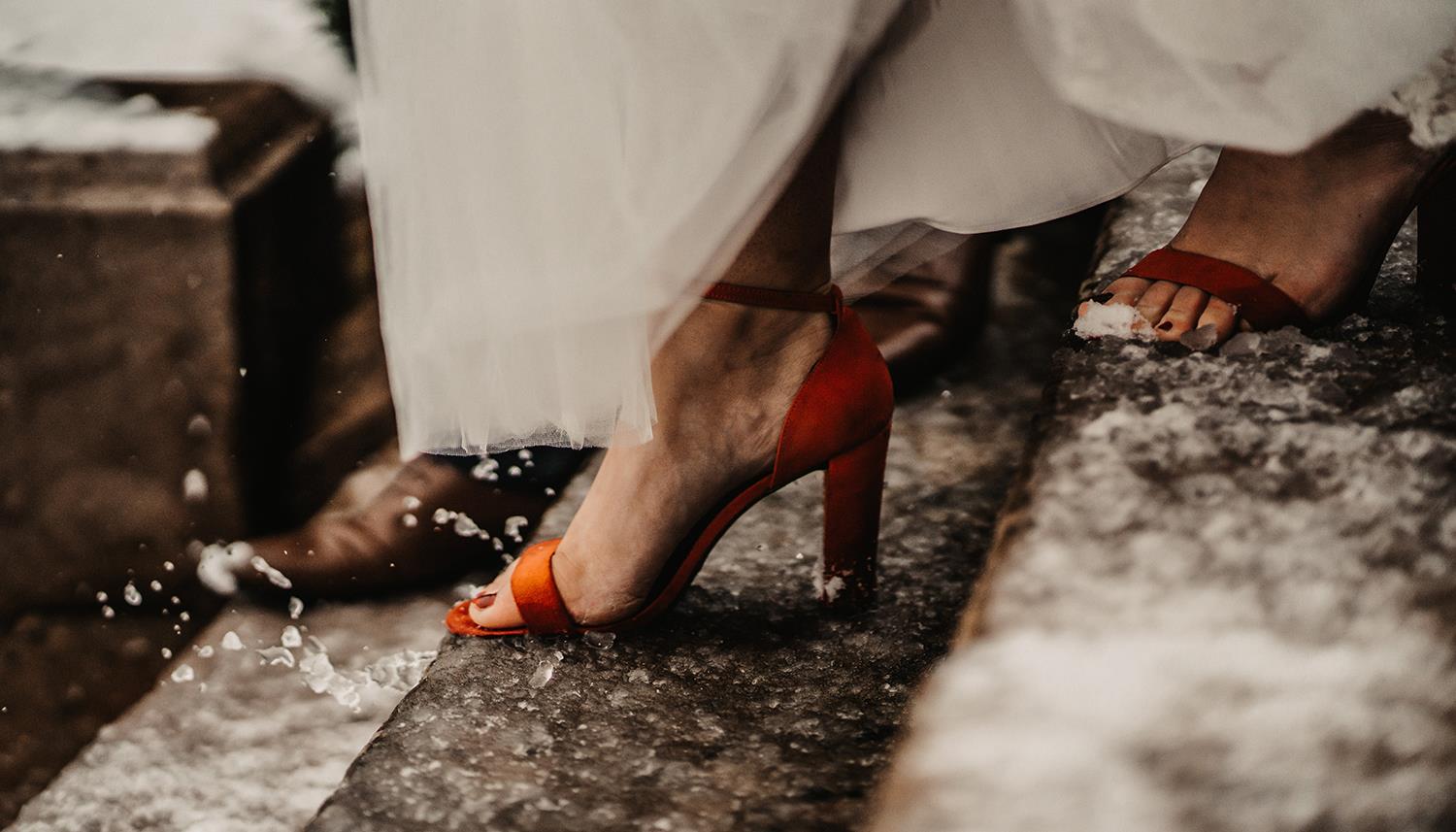 Bride stepping down snow-covered steps. Photo Credit: Willow & Wilde Photography