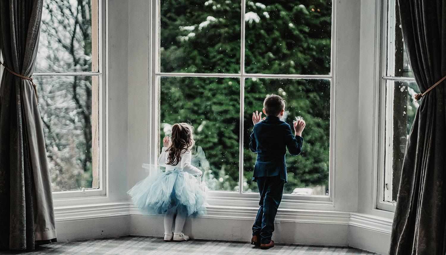 Flower girl and boy watching the snow through the window. Photo Credit: Willow & Wilde Photography