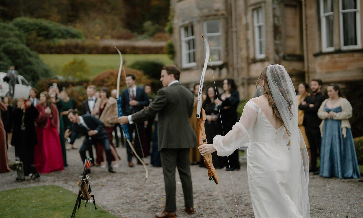 Bride and groom taking part in traditional archery during a Scottish castle wedding