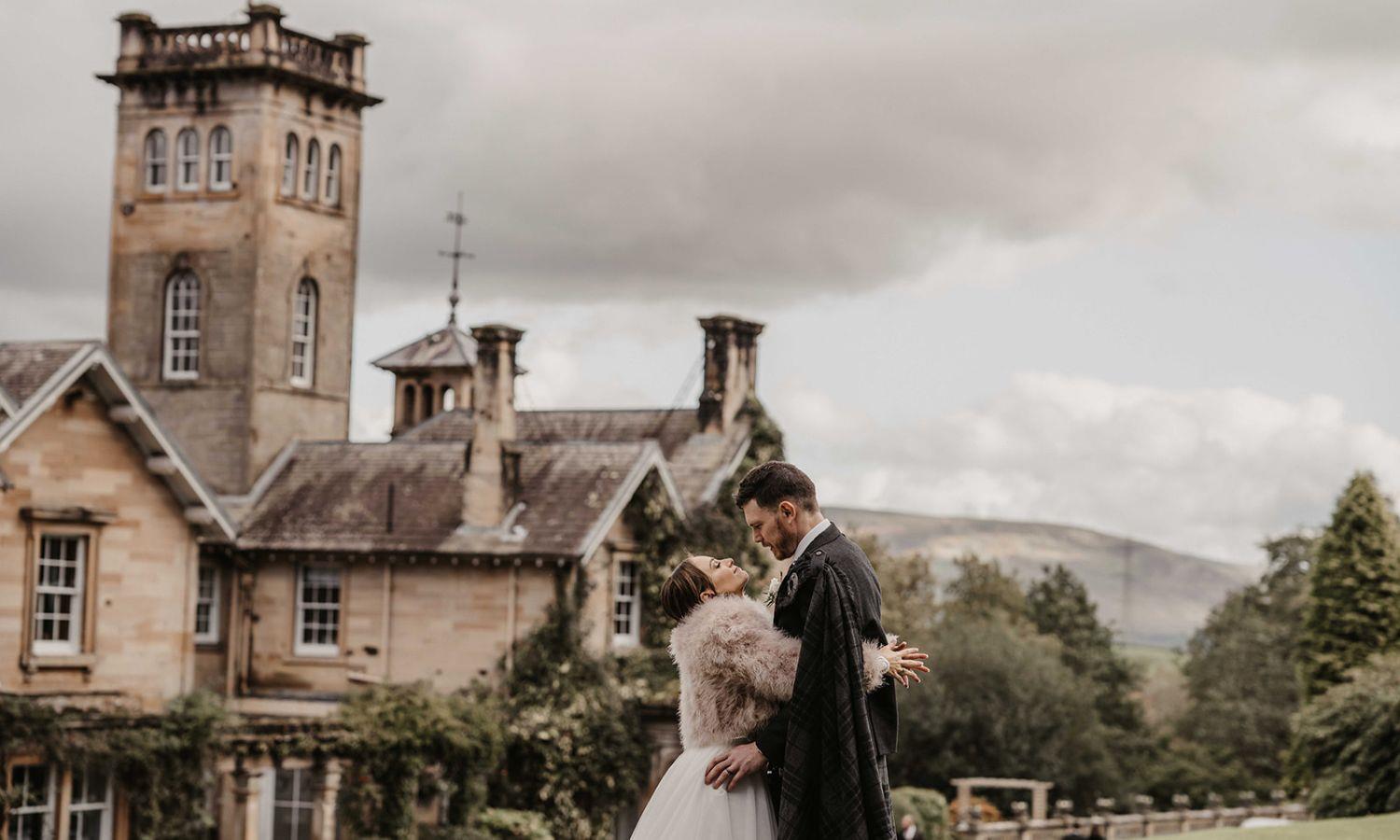 Bride & Groom embrace in front of Auchen Castle, Scotland