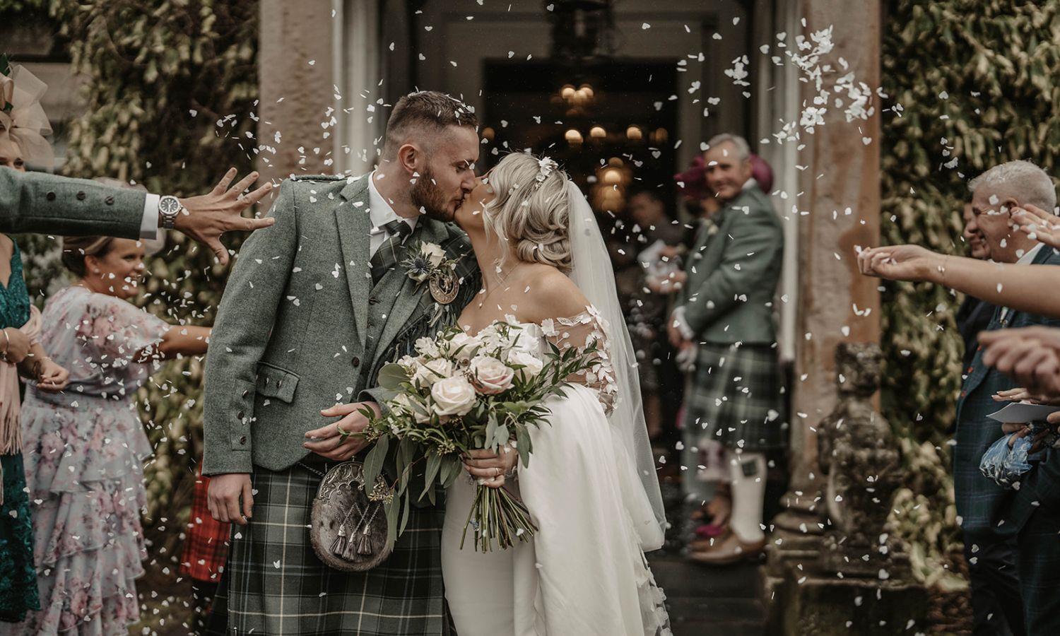Couple kissing with confetti being thrown at wedding