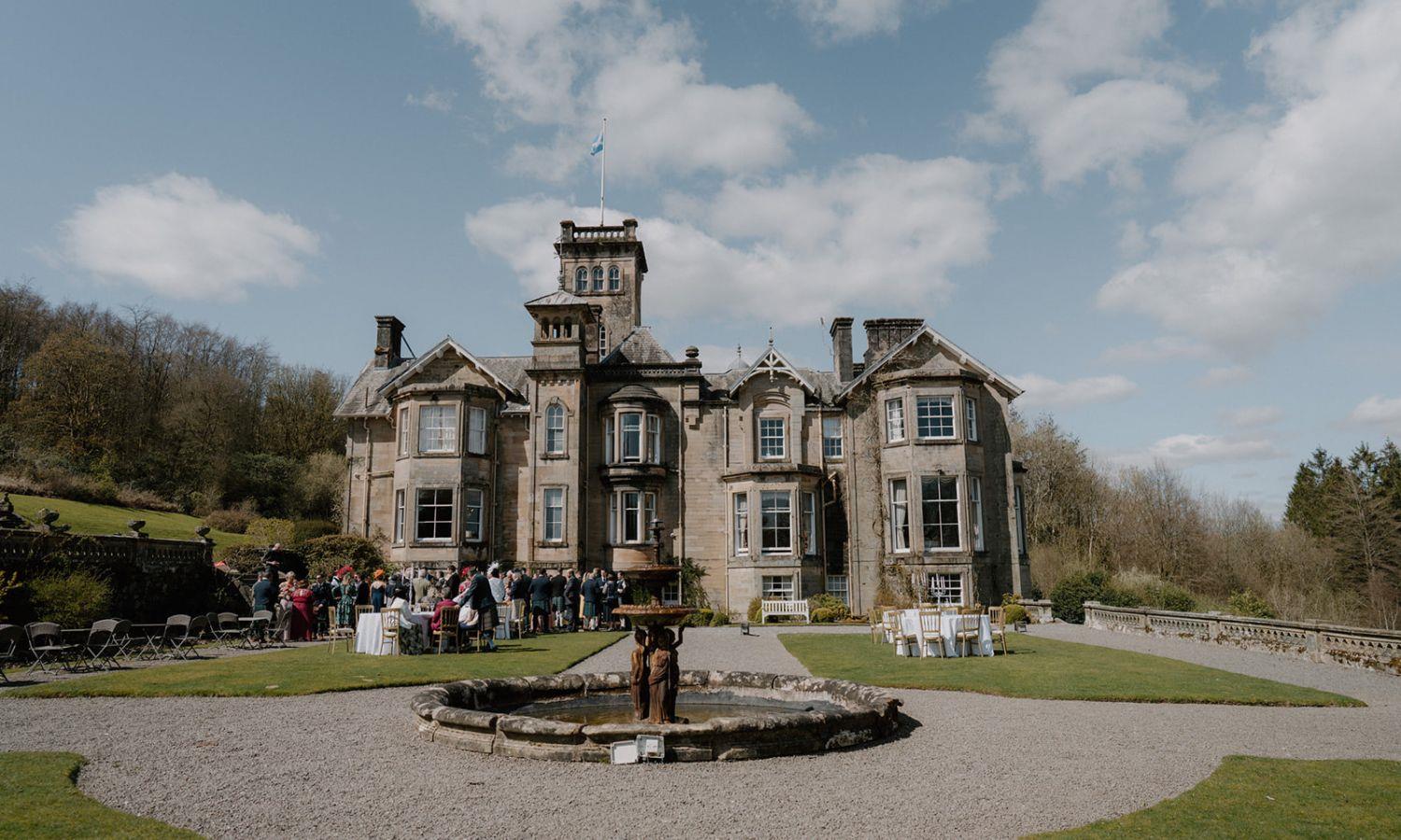 Outdoor wedding ceremony at Auchen Castle with guests gathered in the gardens 