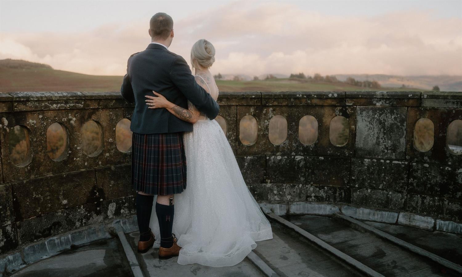 Wedding couple with arms around each other on the turret at Auchen Castle