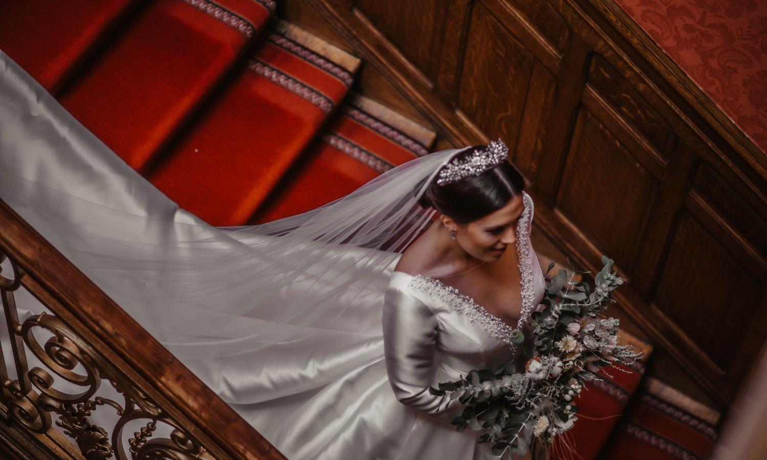 Bride with bouquet descending grand castle staircase