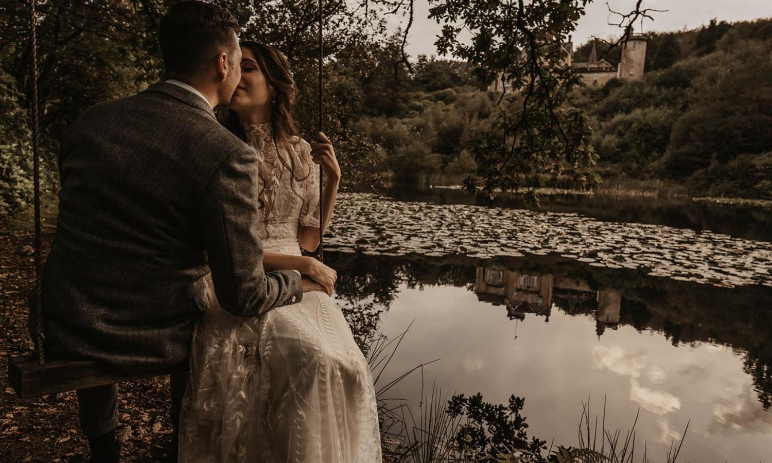 Bride and groom kissing by the lake at Auchen Castle