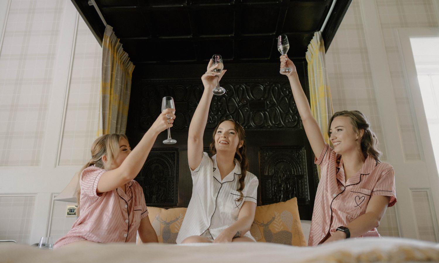 Bridal party toasting with champagne during wedding preparation in luxury bedroom