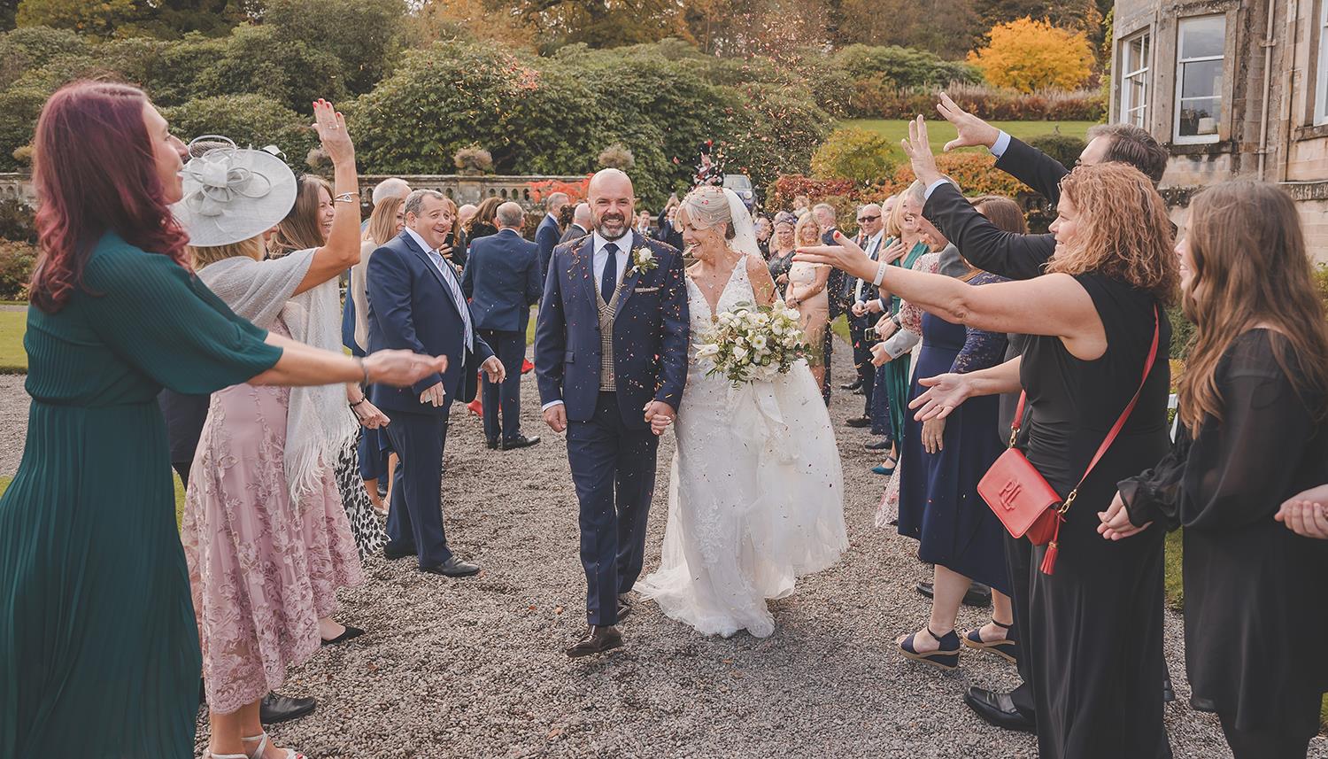 Walking along path with confetti being thrown. Photo Credit: Duncan Ireland Photography