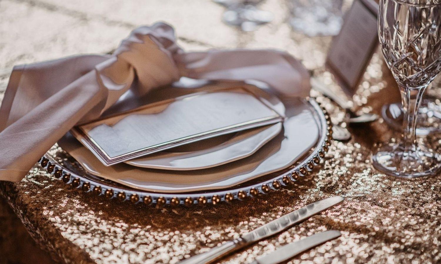 White and gold place setting on dining table with white knotted napkin