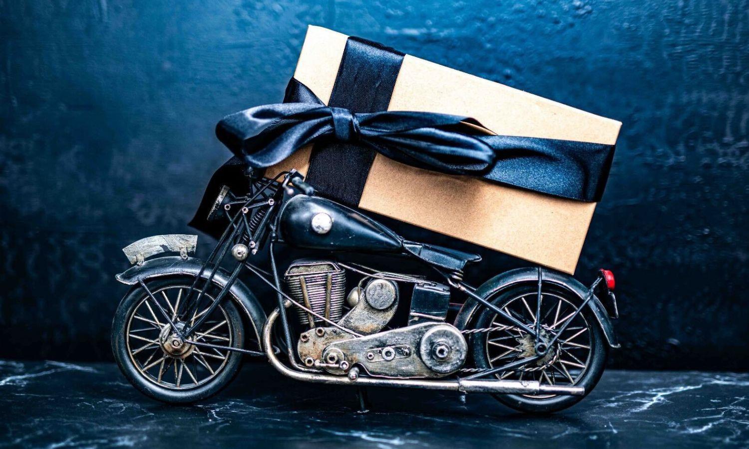 Brown box wrapped in black ribbon on back of toy motorbike