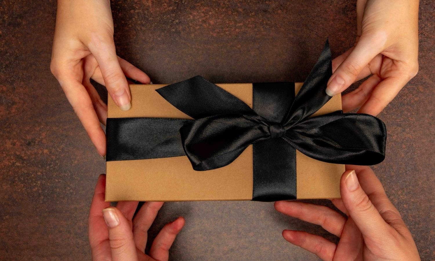 Two pairs of hands receiving a gift box