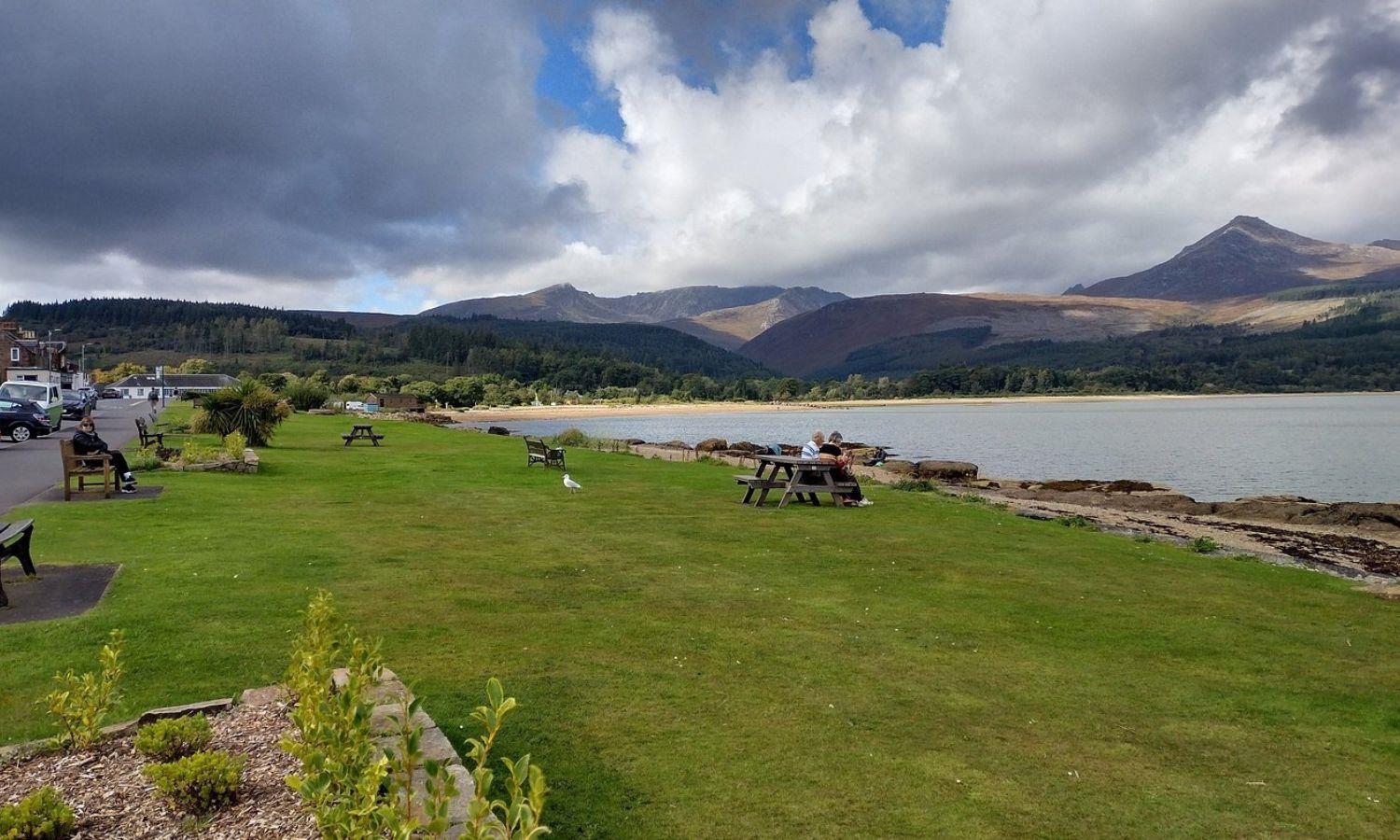 View across Blackwaterfoot Bay on the Isle of Arran with mountains, shoreline and picnic benches