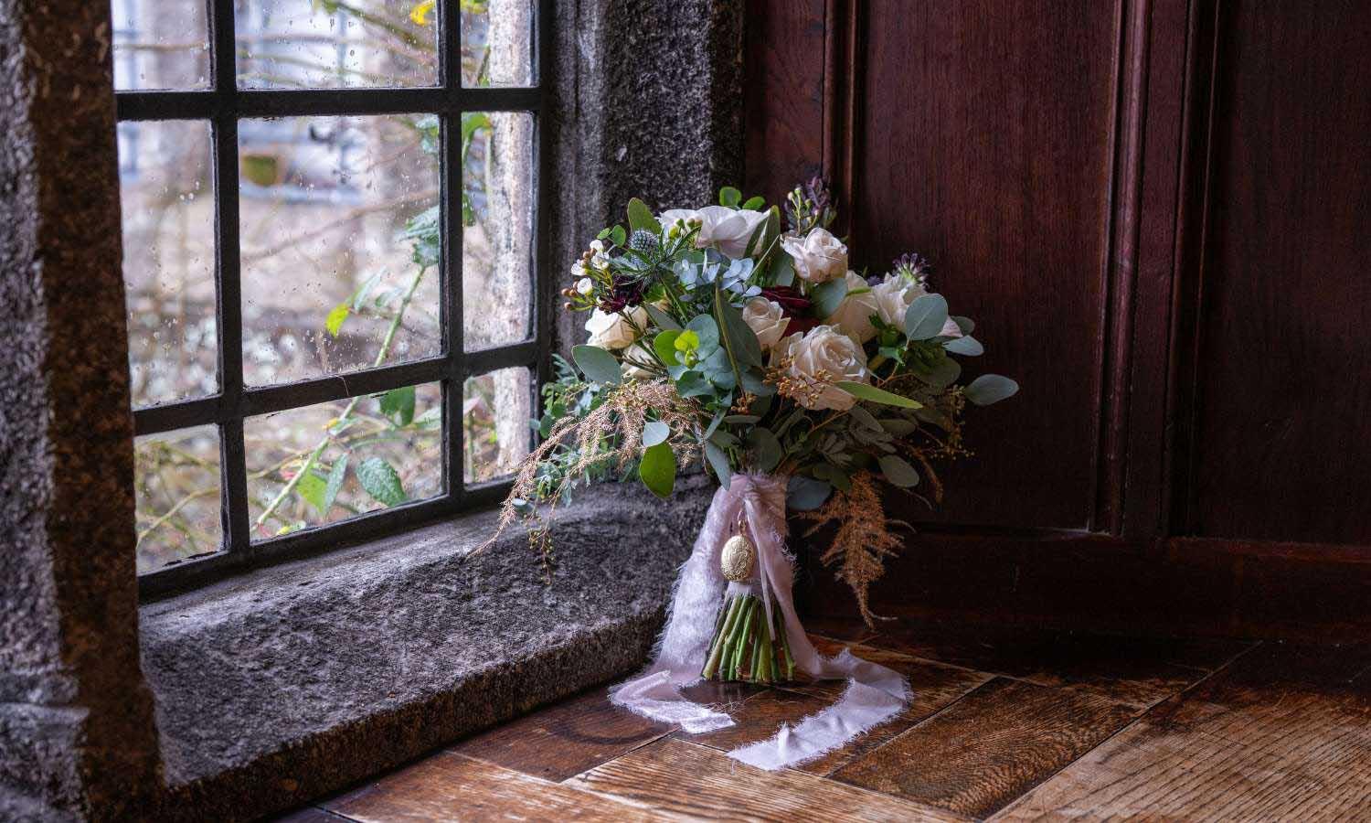 Wedding bouquet of winter flowes in window of Lewtrenchard Manor