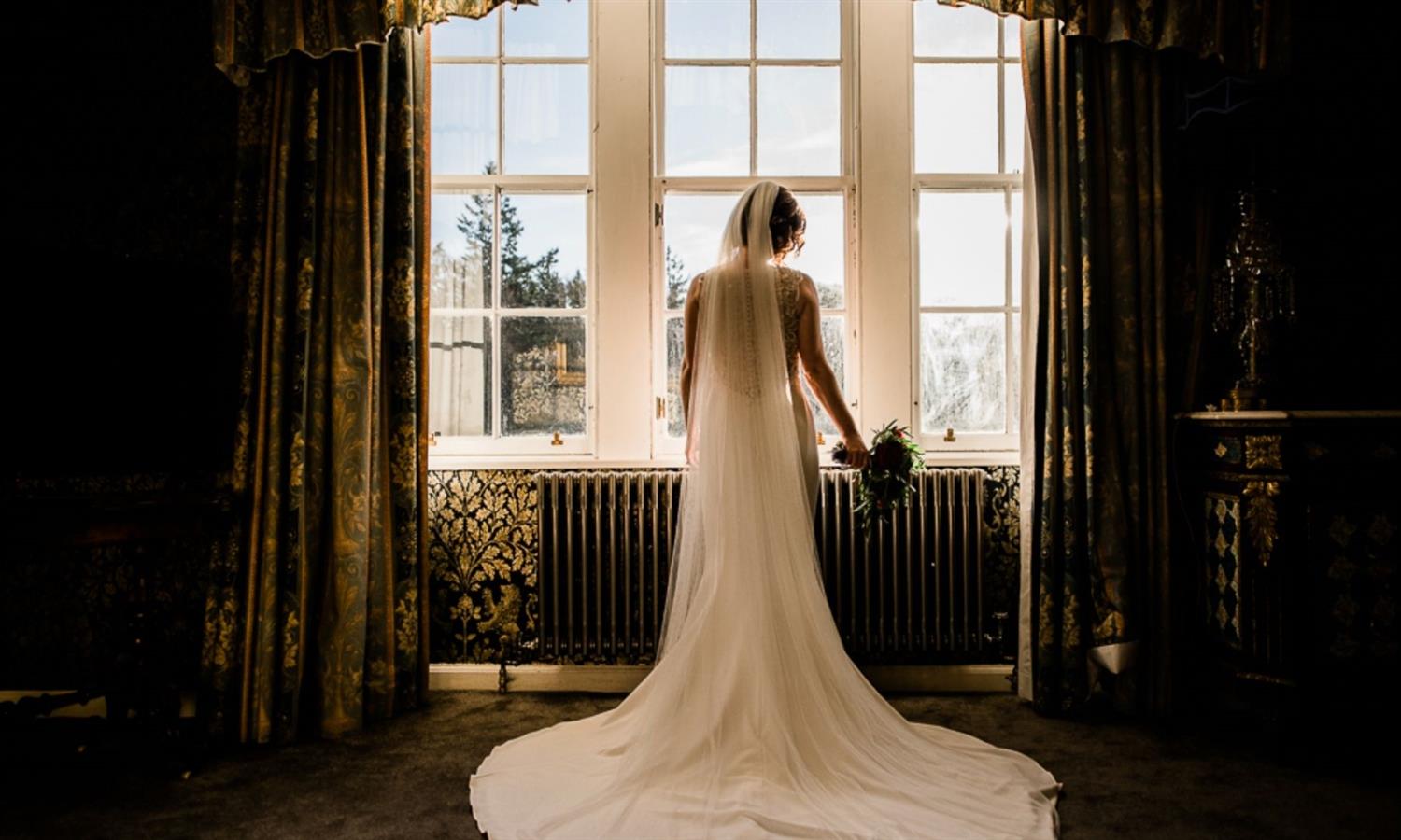 Bride's silhouette in grand window of the castle