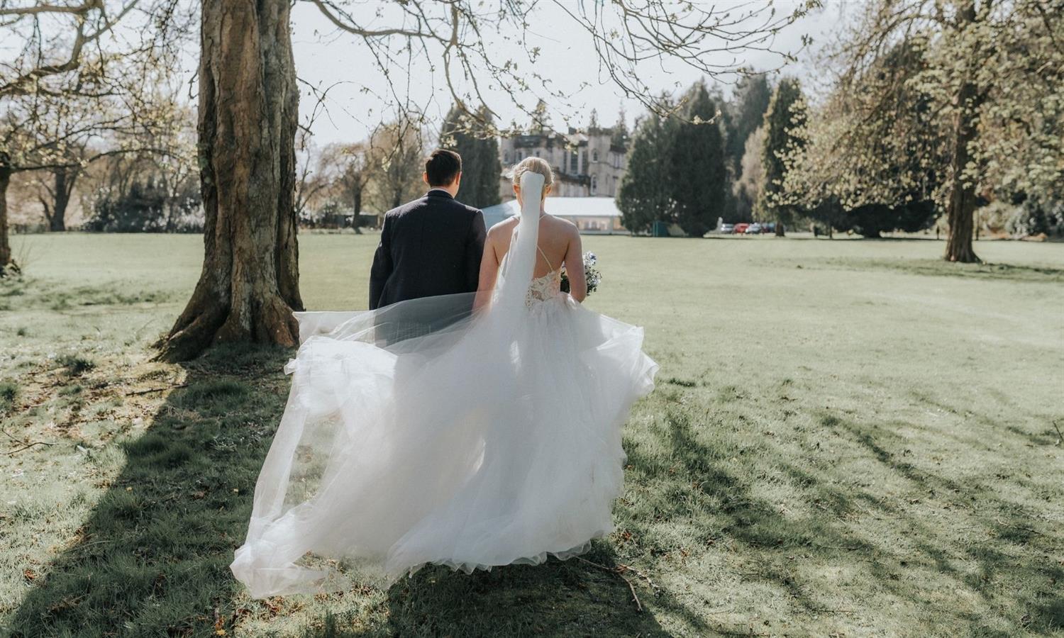 Bride and groom holding hands in the grounds of Melville Castle in springtime