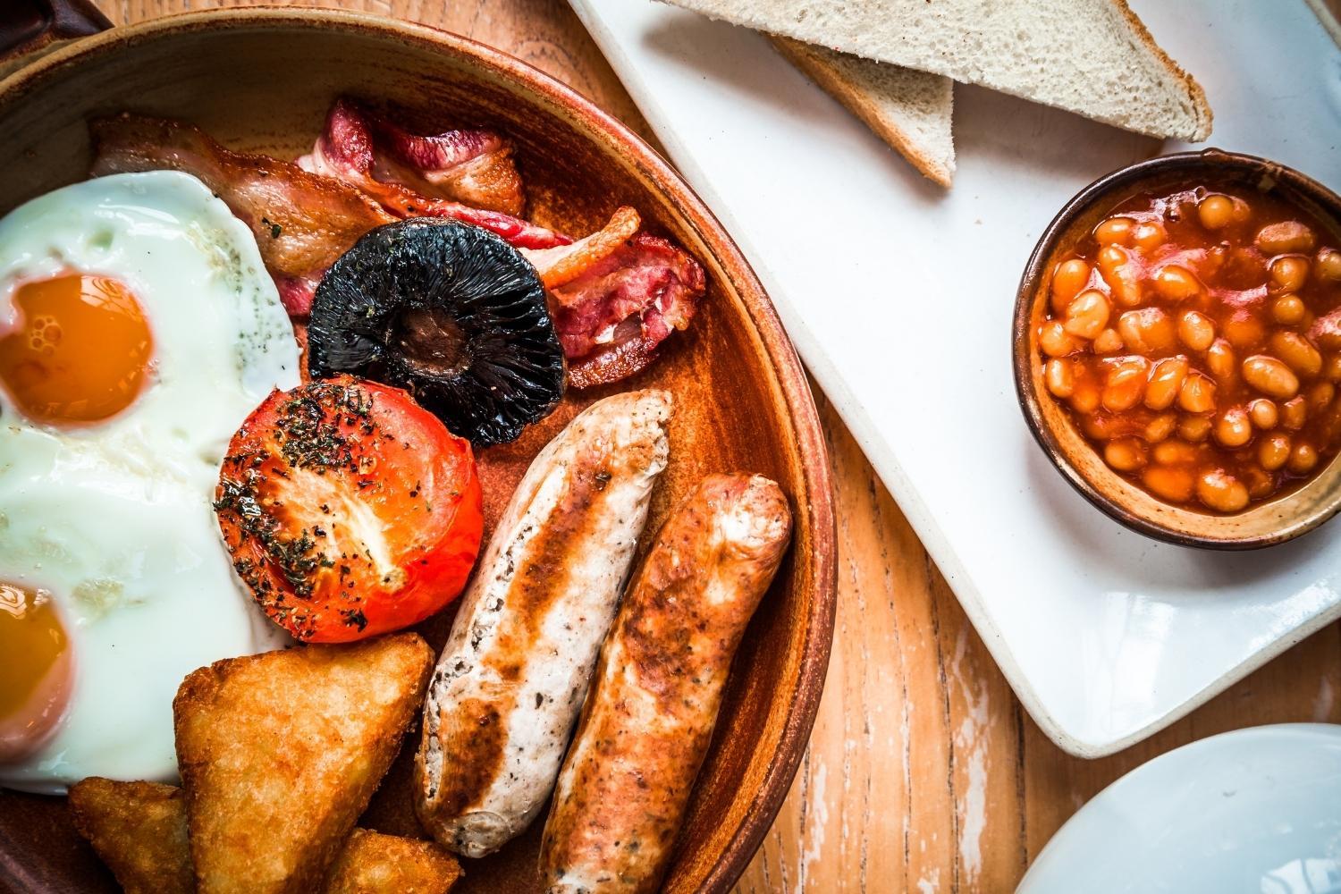 Cooked breakfast with egg, tomato, beans, mushroom, bread, hashbrown and bacon