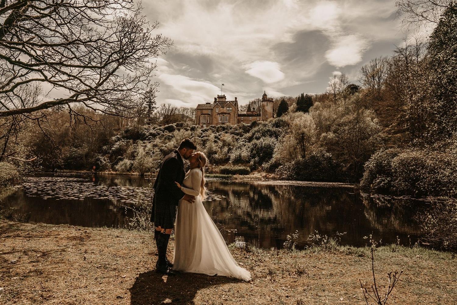 Wedding couple kissing by lake at Auchen Castle