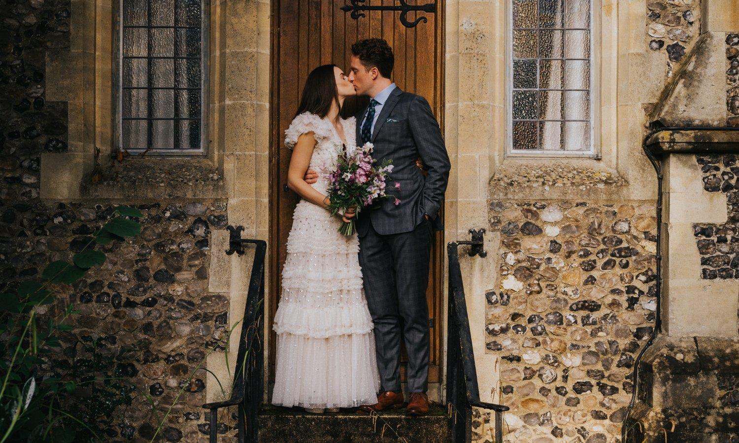 Wedding couple kissing holding bouquet of flowers