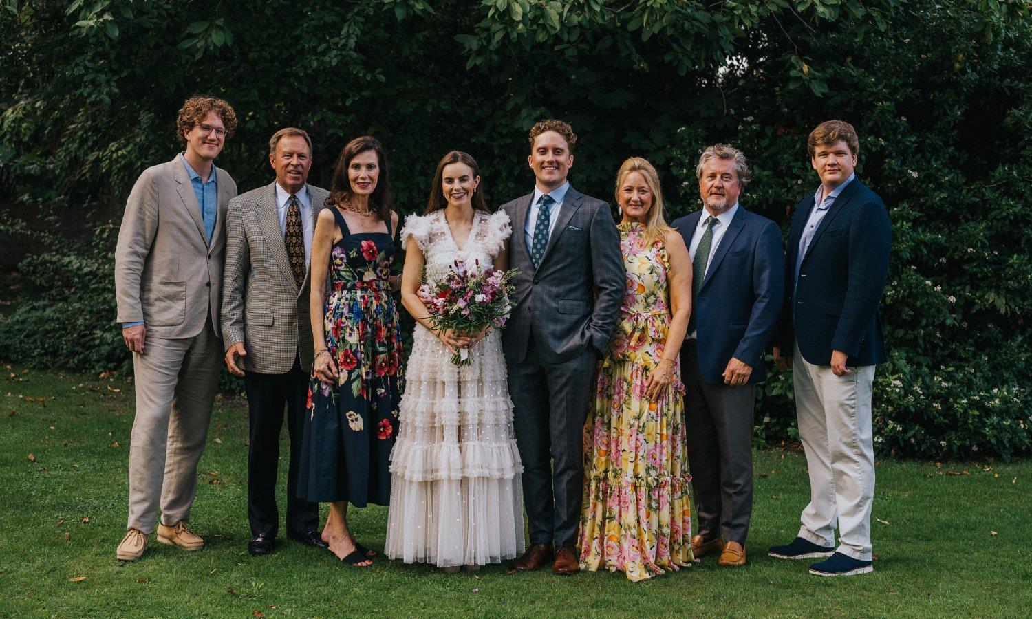 Bride and groom with wedding guests in hotel gardens