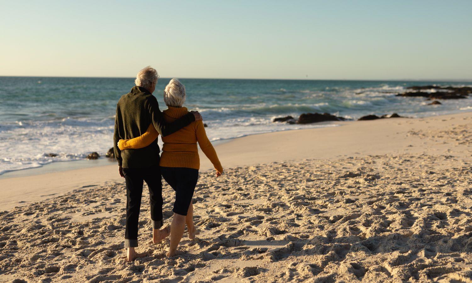 Couple walking on windswept beach, arm in arm