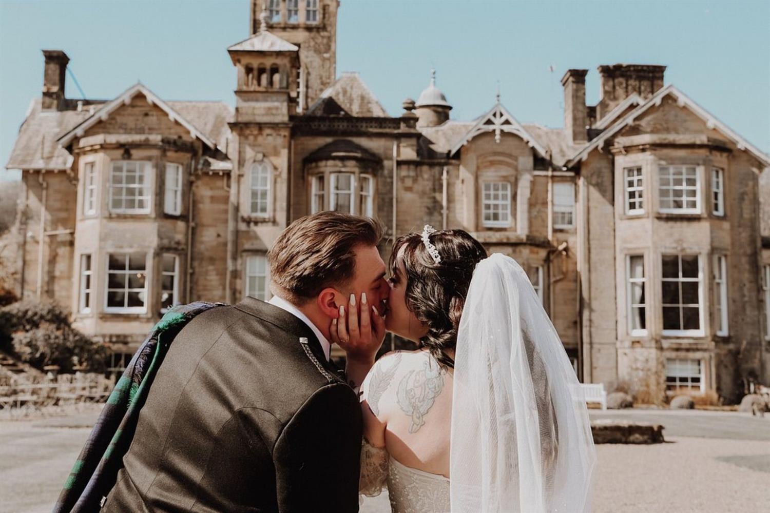 Newlyweds kissing outside Auchen Castle