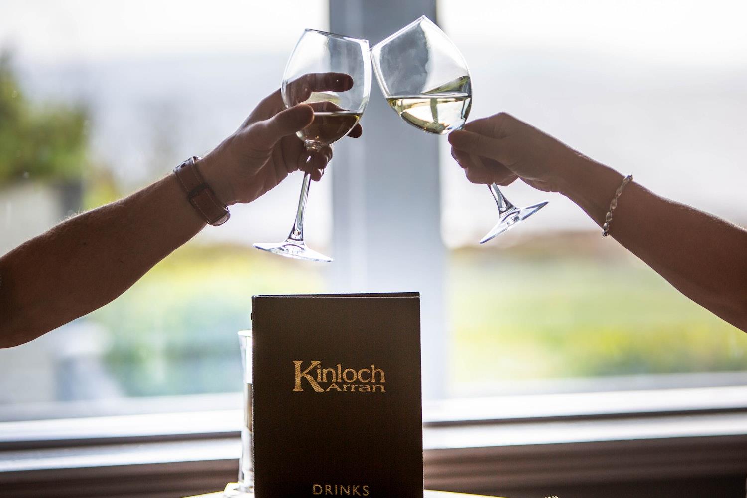 Two wine glasses clinking in front of sea views 