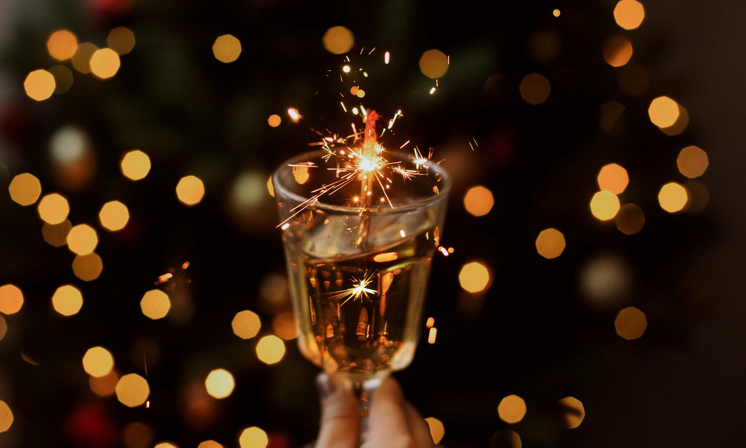 Glass being held up against a background of fairy lights