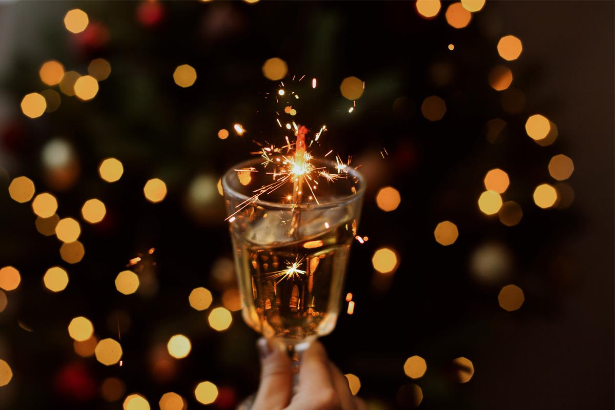 wine glass held up in front of fairy lights 